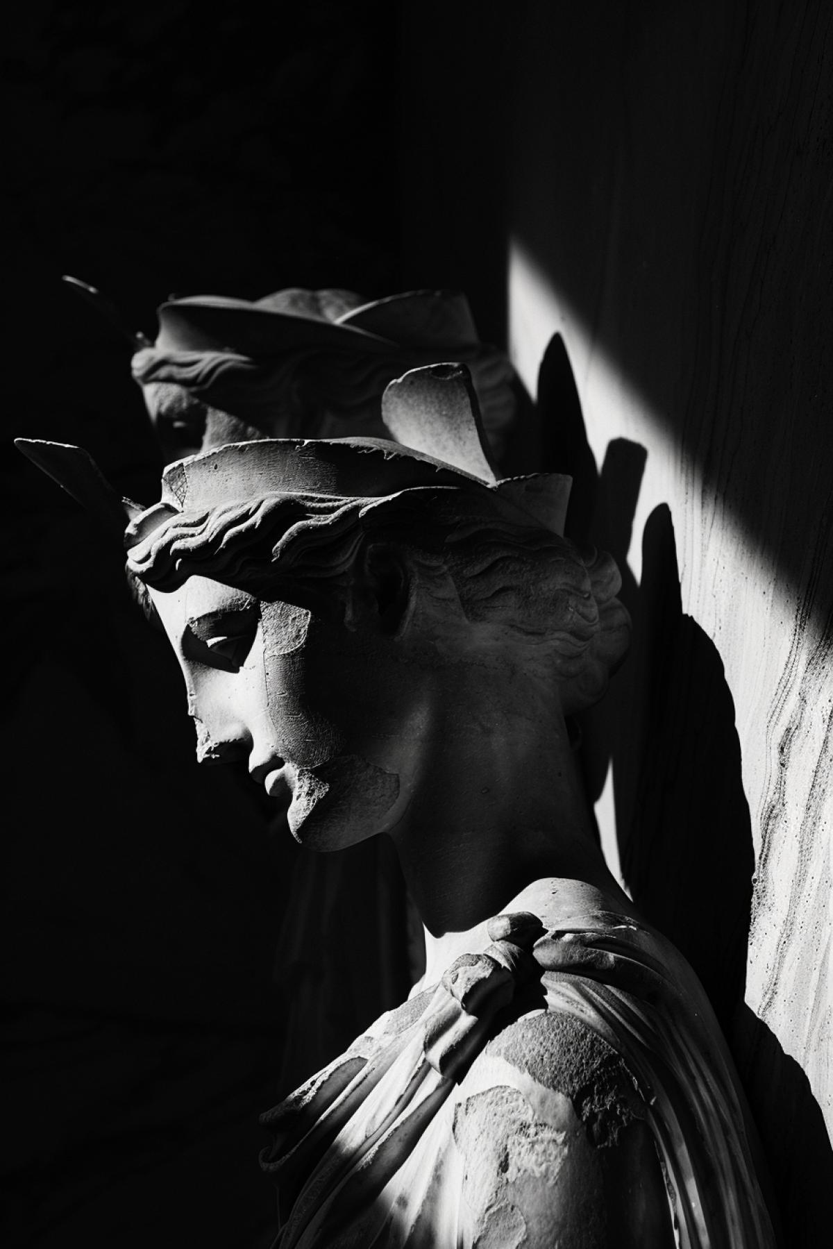 Greek statues of goddess cast deep shadows, harsh light, abstract, photorealism