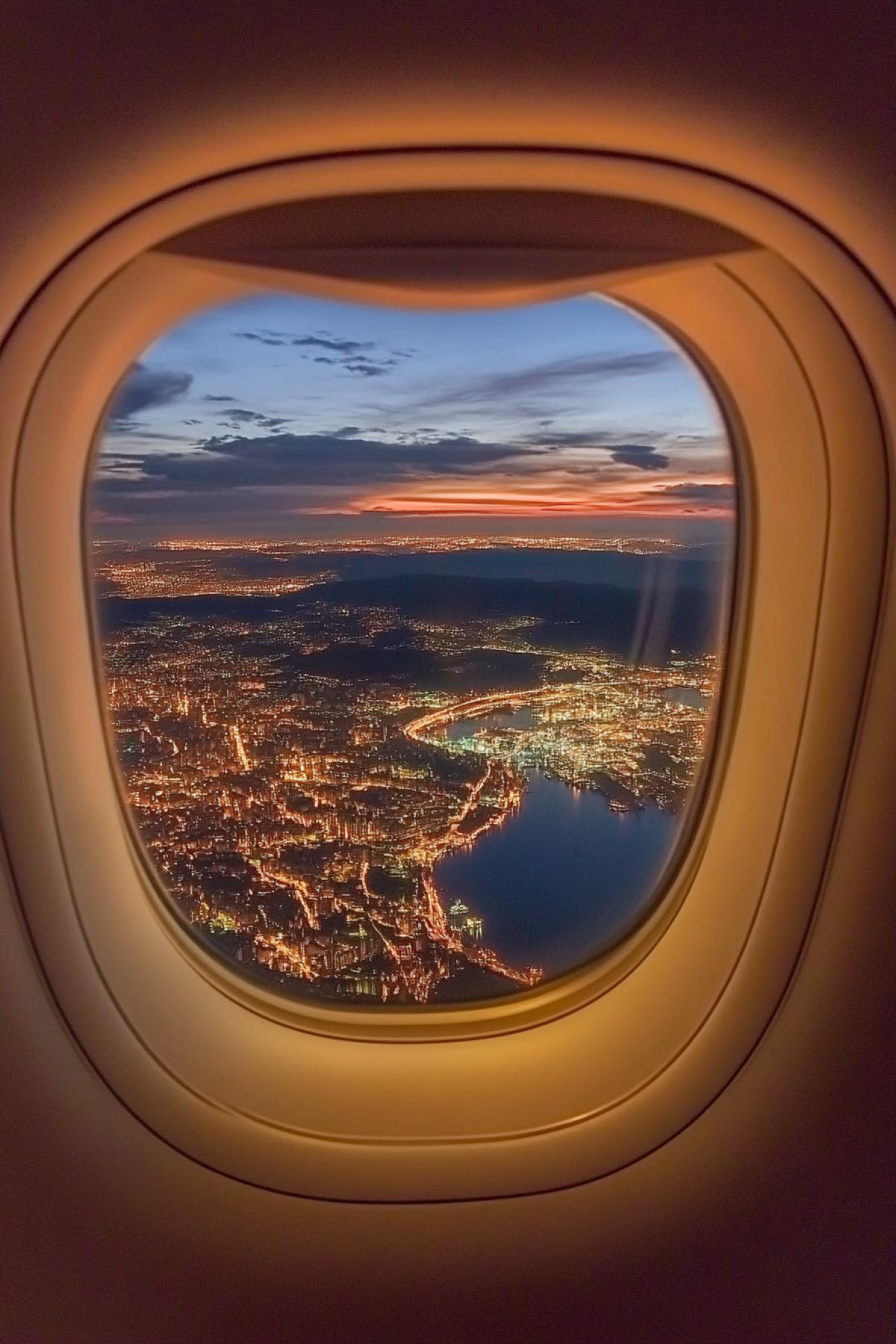 View through the airplane window with a marvelous landscape at the night megapolis