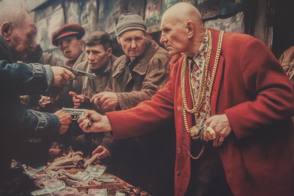 Retire in a red jacket gold chain on the neck and a large ring, bald, with a gun collects money from merchants in the market, Russia 90s