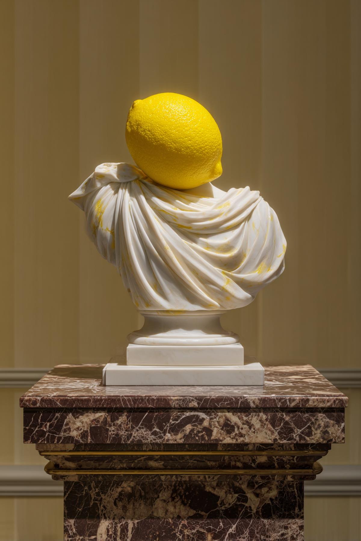A whole lemon with the Venus de Milo sculpture meticulously carved from its peel, the yellow rind forming her drapery, displayed on a marble pedestal under spotlight, hyper-realistic 8K, museum exhibition style
