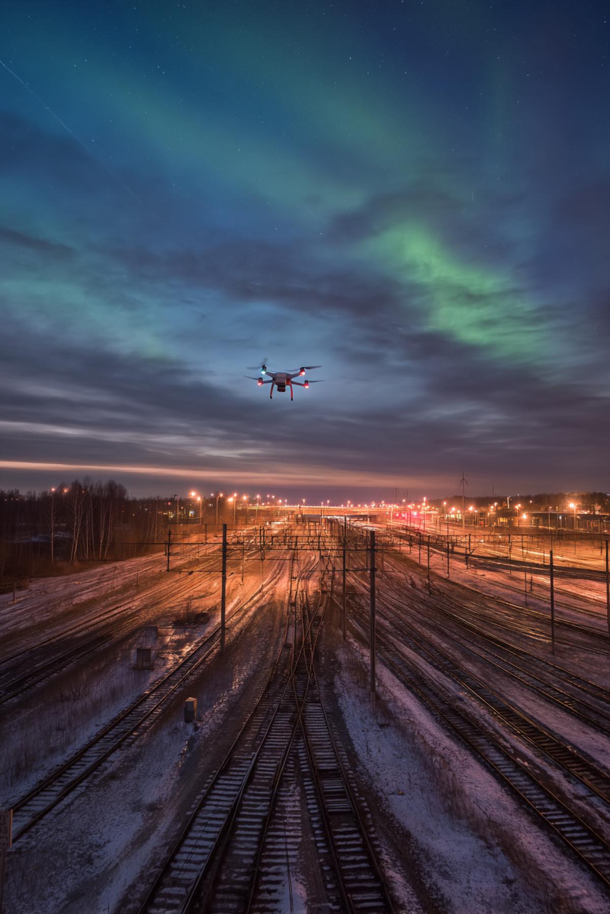 The drone-shooting of a big railway junction where 12 paths diverge by a fan. On each there is a train from different decades (steam locomotive, Soviet train, Maglev). In the sky the northern lights that emphasize the geometry of the choice. Removed on the Phase One XT, 30-second shutter speed, cold technogenic tones.