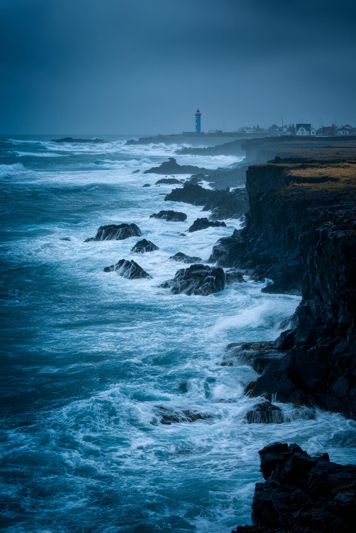 The dramatic storm off the northern coast: waves with white crests break on dark basalt cliffs, rain flies over the water with oblique jets. In the distance a lighthouse, his light luxuryly breaks through the fog. Removed on Nikon Z9 with long shutter speed (1/4 second), ISO 800. Style: atmospheric action-frame, cold blue-gray palette