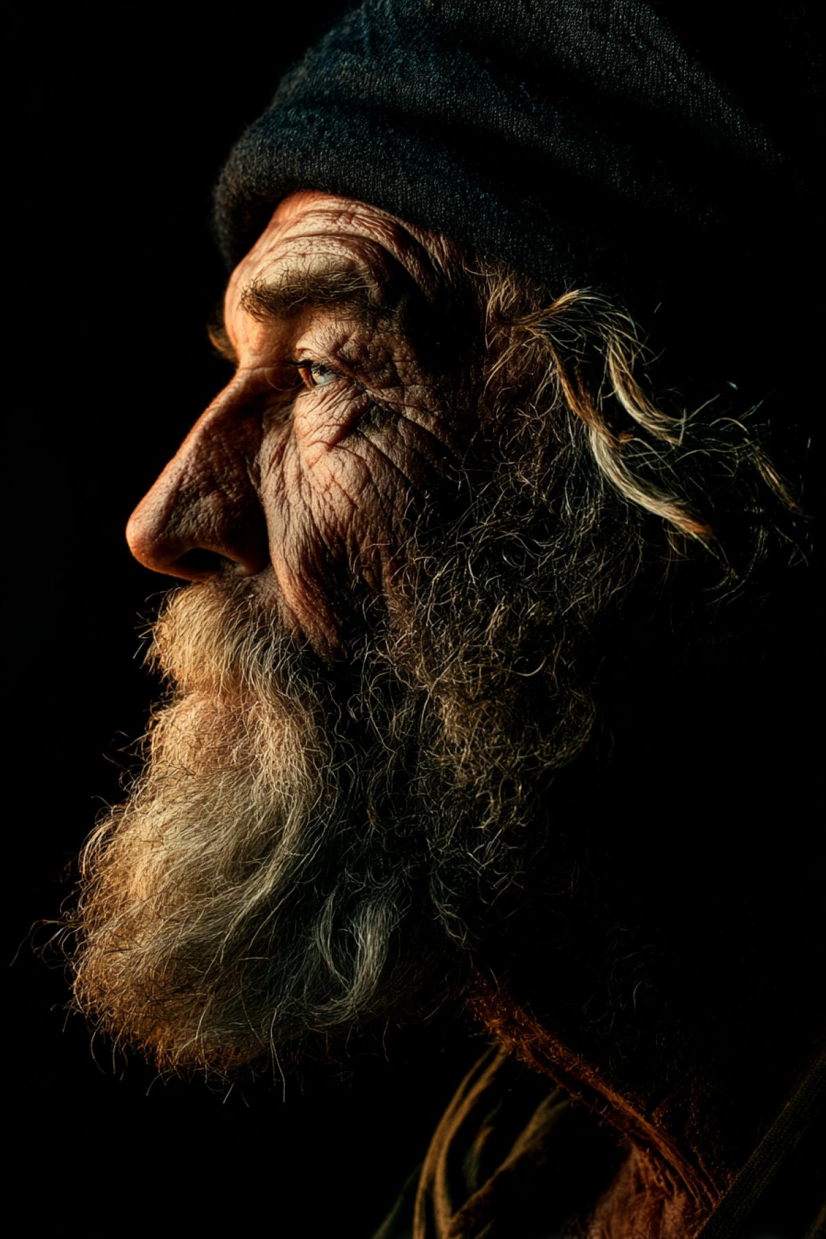 Portrait in the profile of an old fisherman. Lighting from above is half a control.